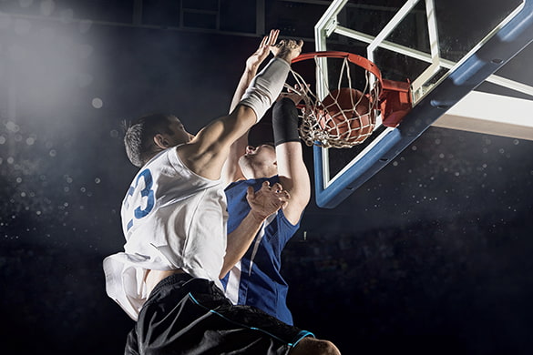 two basketball players jump at the hoop